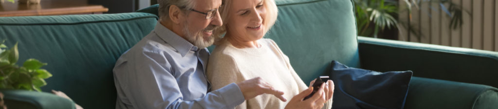 Elderly couple looking and pointing towards a mobile phone