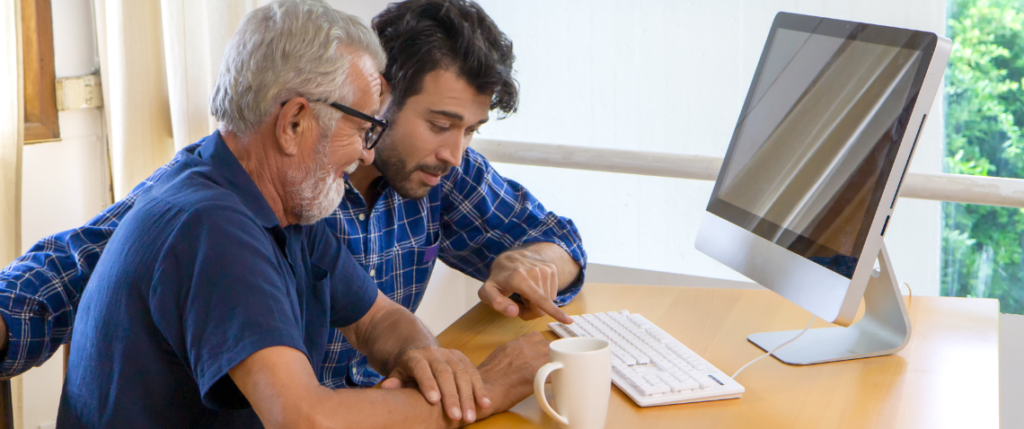 young-man-assisting-senior-with-technology