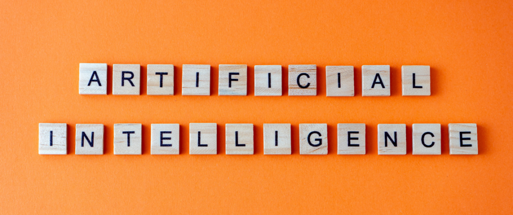 Artificial Intelligence spelled out in scrabble letter blocks on an orange background.