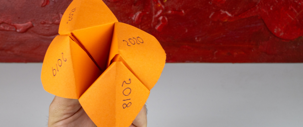 Paper folded fortune teller in orange with the years 2018, 2019, 2020, 2021 listed on the 4 corners.